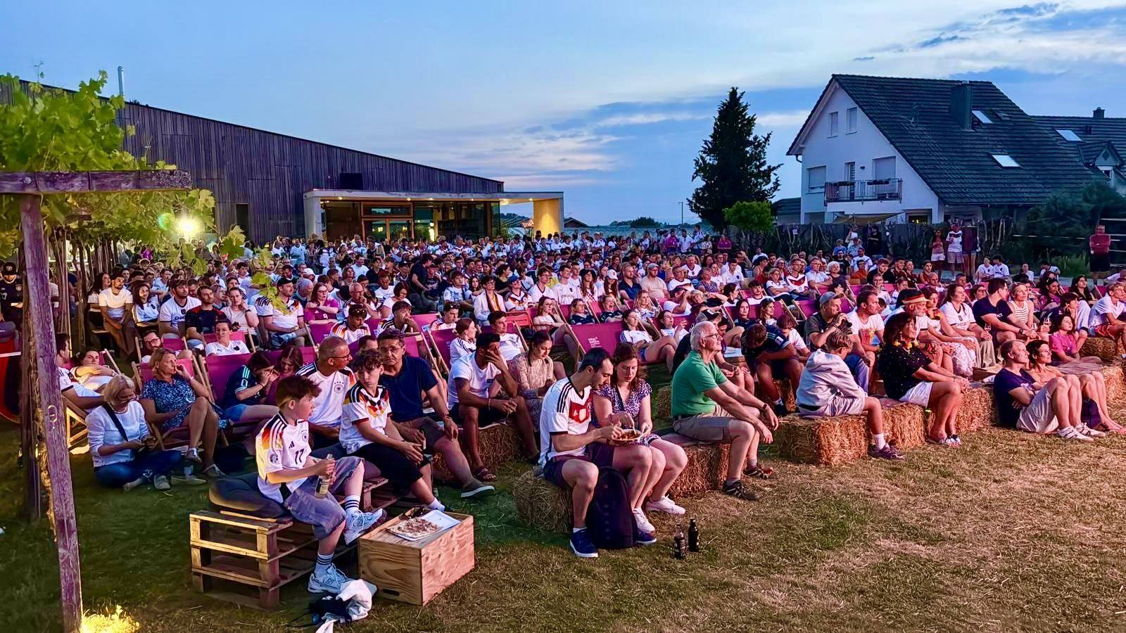 Hunderte Fans in Liegestühlen und auf Strohballen beim Public Viewing